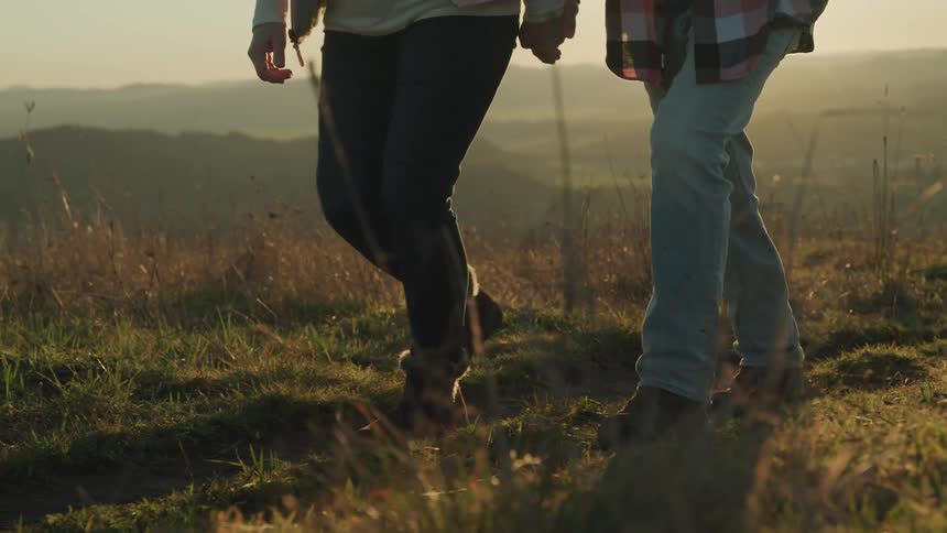 A man and woman walk across a field holding hands