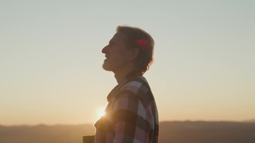 A man is standing outdoors at dusk