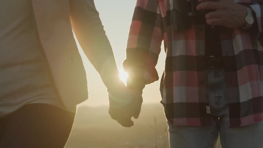 A man and woman hold hands walking through a field