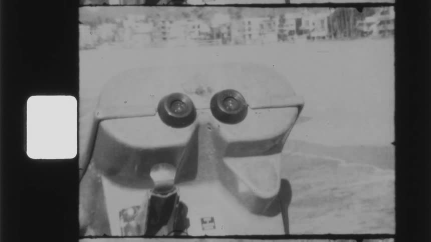 A coin operated viewfinder on a beach on the coast of a city