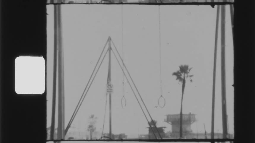 A swing set sits perpendicular to rings on a playground