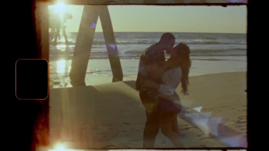 A man grabs his girlfriends face and kisses her on the beach