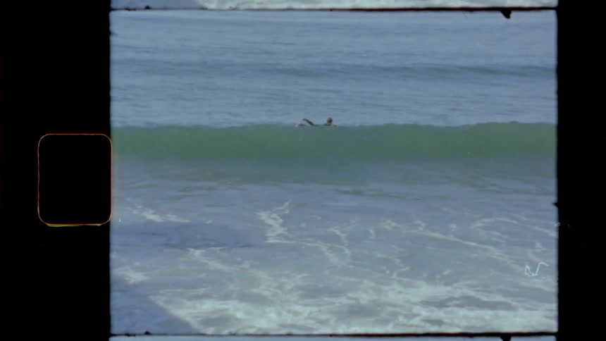 A person laying on a surfboard going over a wave on the beach