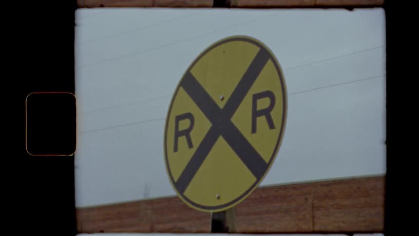 A railroad crossing sign in a town on an overcast day