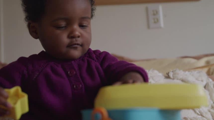 Toddler plays with shape sorting toy in room