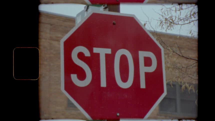 A stop sign in front of a brick building on an autumn day