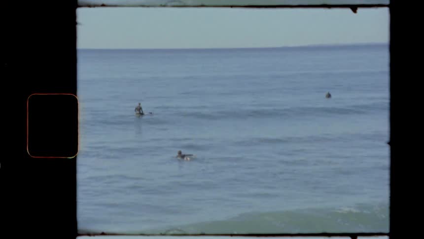 Three people in the water surfing and swimming