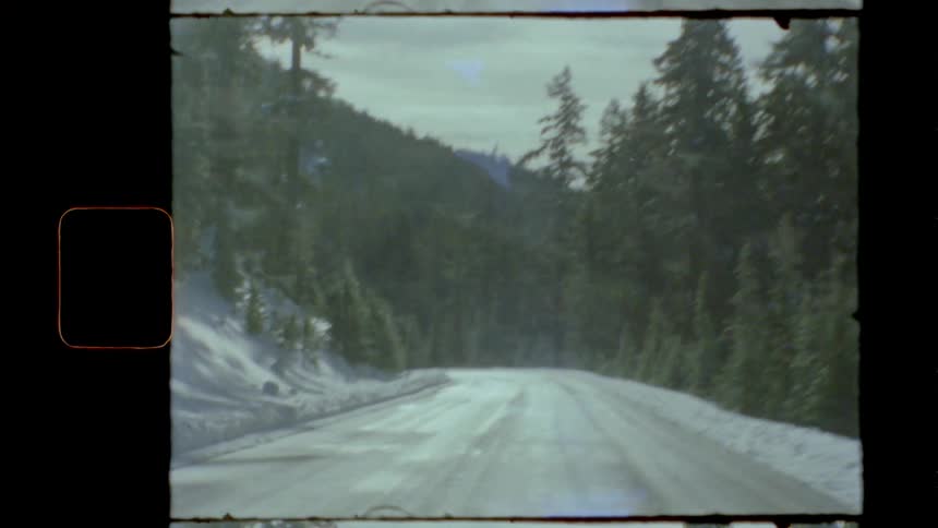 A car travels on a snowy mountain road in a forest