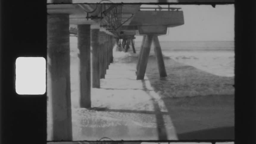 Black and white footage of the ocean near a dock