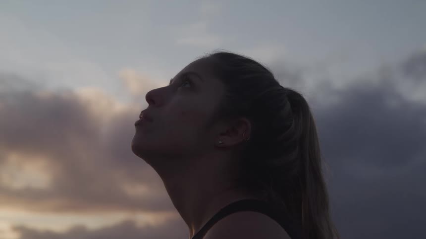Woman looks up at the sky at dusk