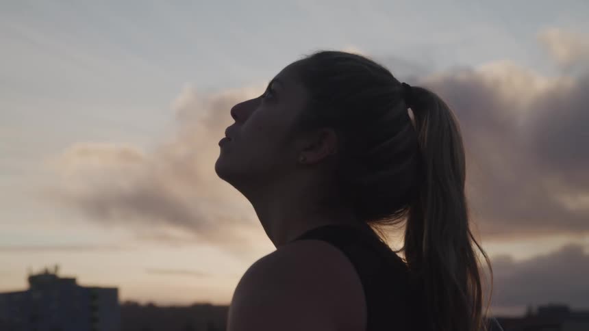 A woman is standing outdoors at dusk