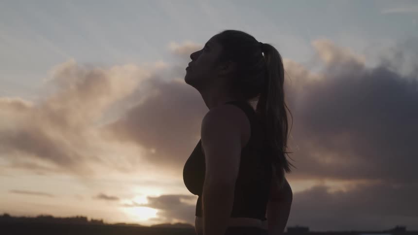 A woman is standing outdoors at dusk