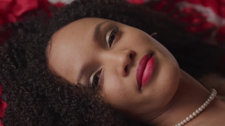 A woman all dressed up lying down and looking ahead of her