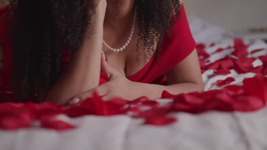 A woman is laying on a bed covered in roses