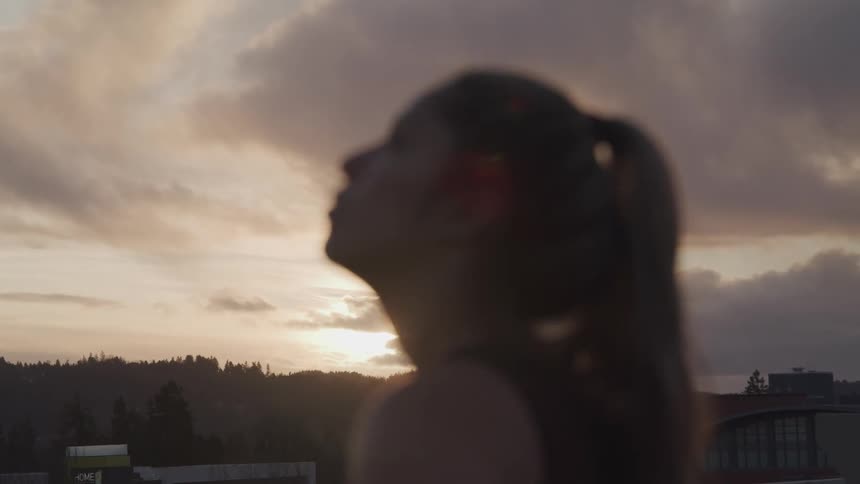 A woman is standing outdoors at dusk