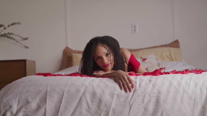A woman is laying on a bed covered with roses