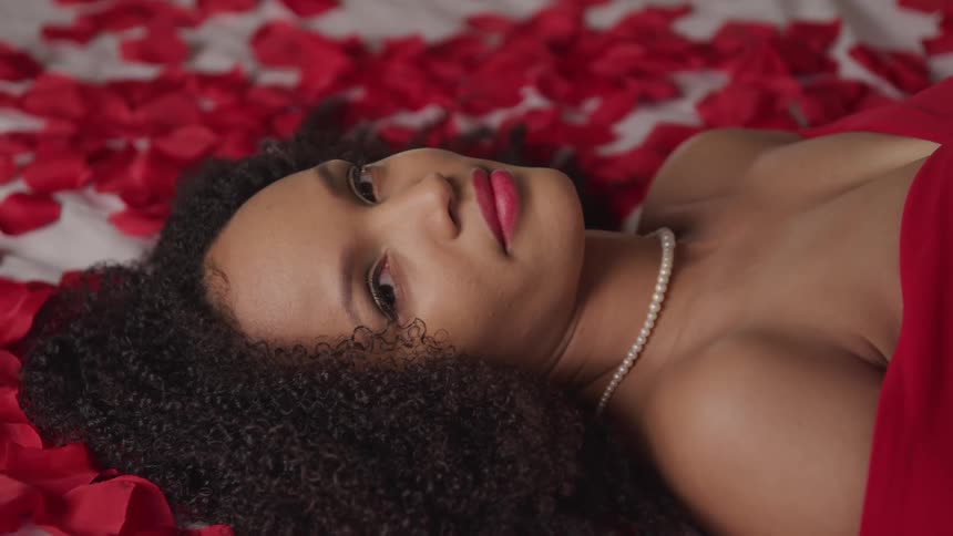 Black woman laying on rose petals for a photo shoot