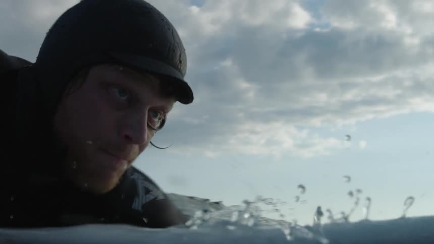 A man is paddling on a surfboard in the water