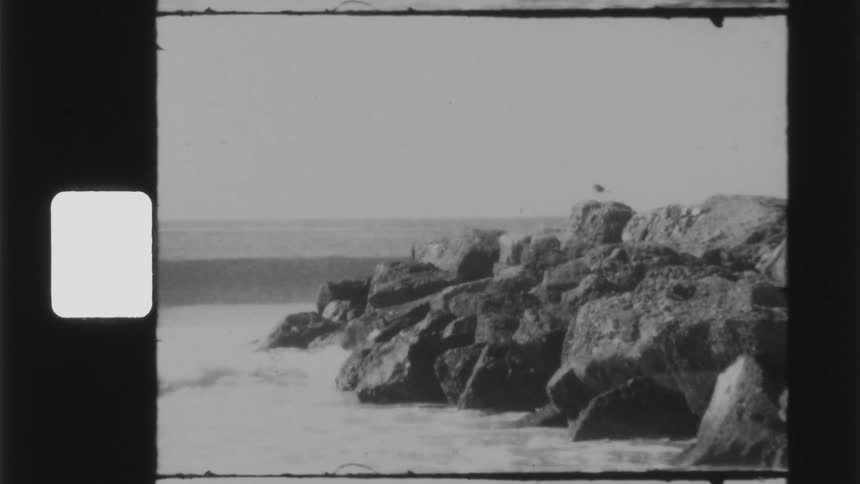 Waves crash against large boulders on shore
