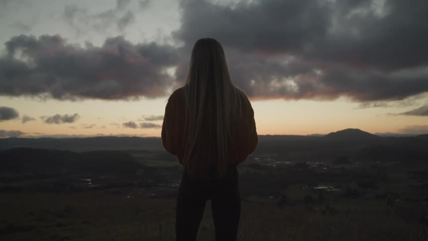 The silhouette of a woman stands out against the cloudy sky