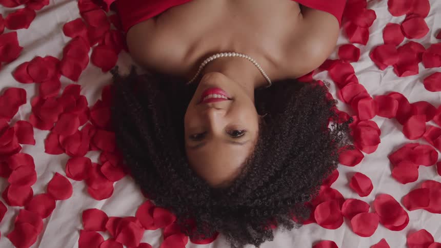 A woman is laying on a bed with rose petals on it
