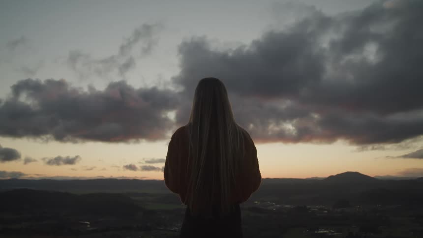 A woman is standing outdoors in a rural area