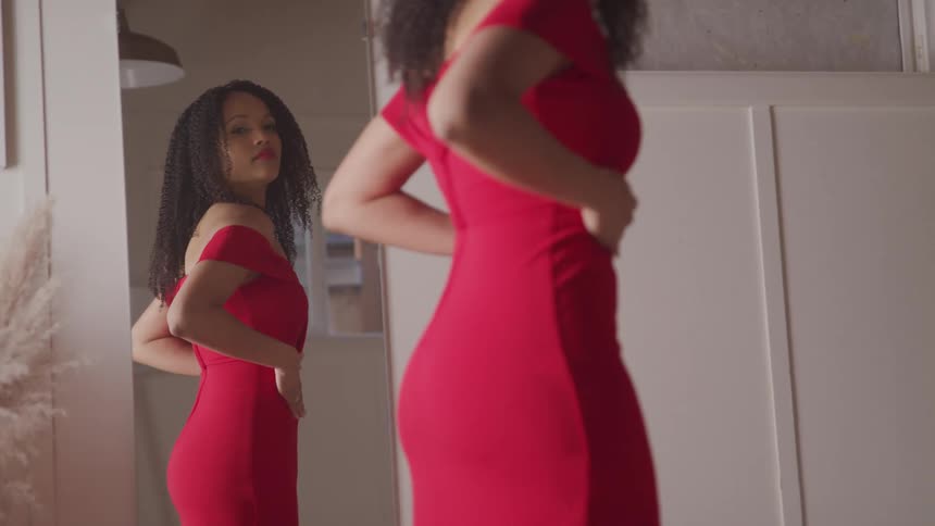 A woman is wearing a dress and looking in a mirror