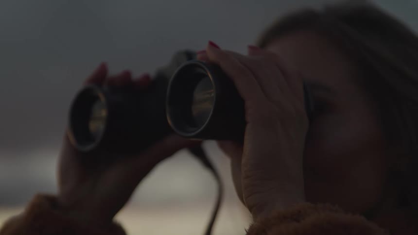 Woman looks through binoculars outdoors