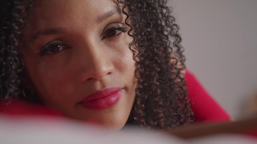 A resting young woman slowly opens her eyes to look into the camera