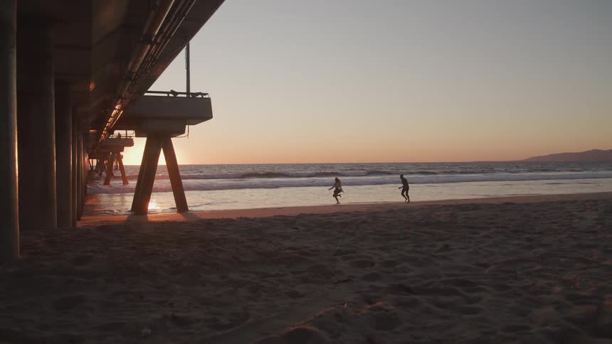Two people run on the beach along the ocean edge