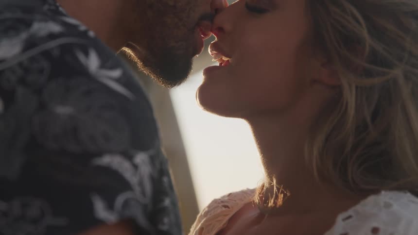 Man and woman are kissing outdoors at dusk