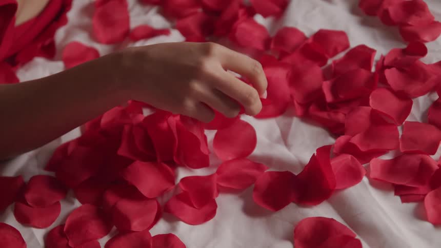 A woman laying in a bed with flower petals and sheets