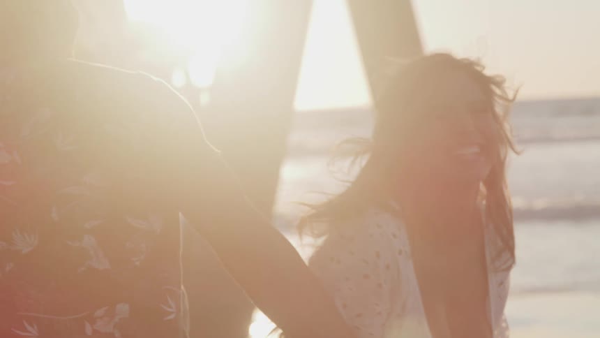 A man and woman laugh and dance on the beach