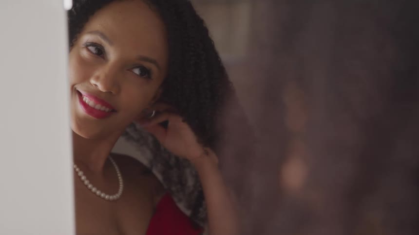 Woman with a necklace makeup and curly hair smiles and looks in the mirror