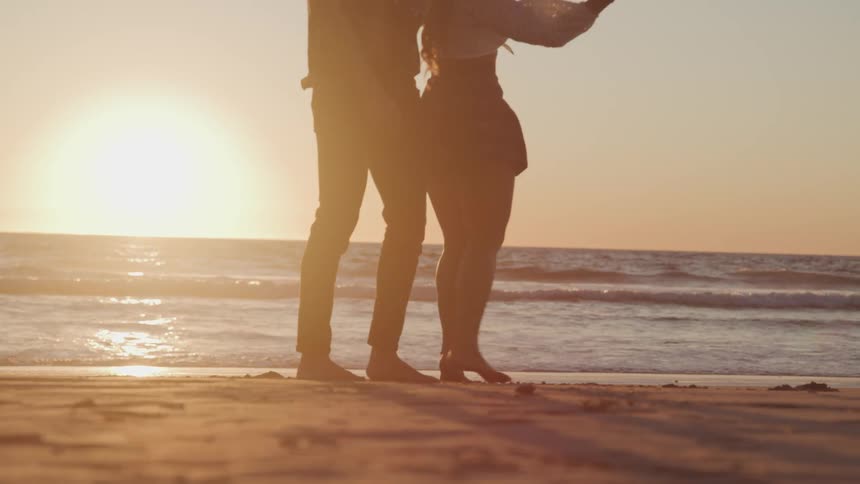 A couple dance on the beach together at sunrise
