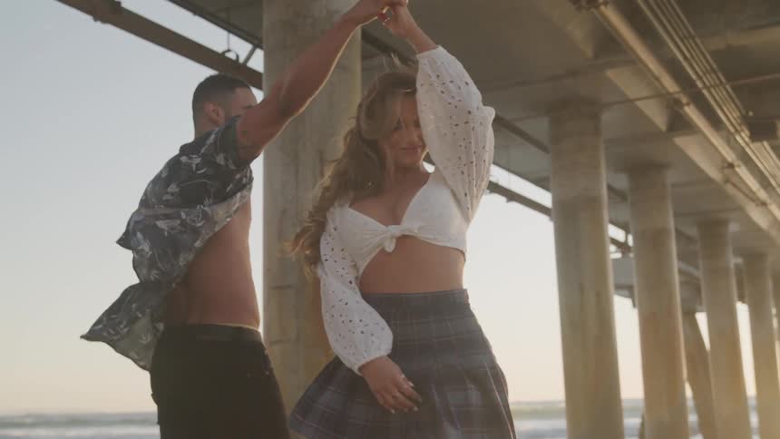 A couple hold hands as they walk on the beach