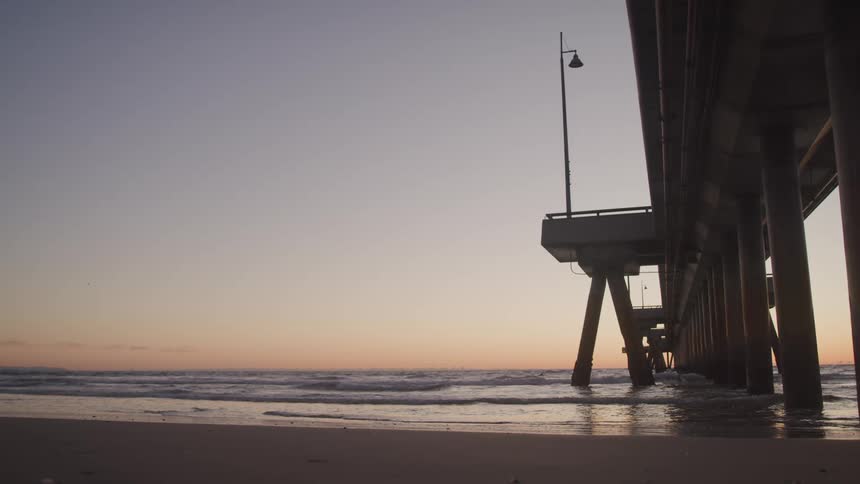 A pier sticking out from the land over the sea at dusk
