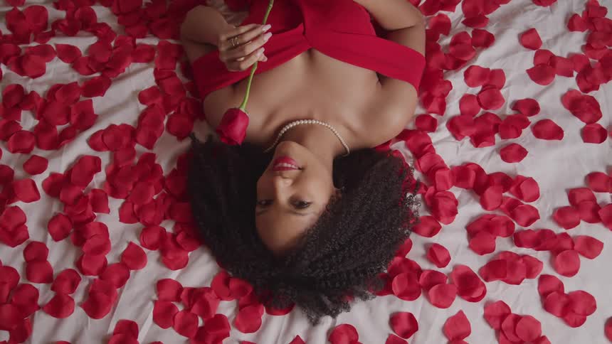 A woman is laying in a bed full of rose petals