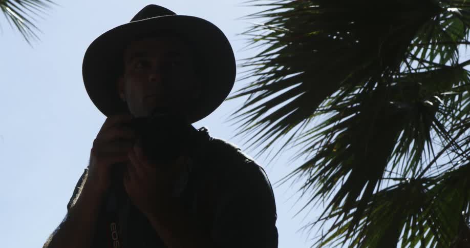 A photographer raises his camera to his face to take a photograph while outdoors