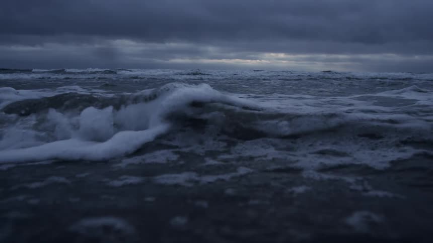 Waves slowly pass over the sand at sunset
