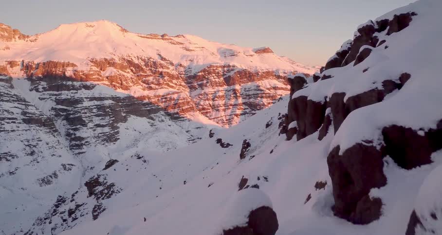 An aerial view of a mountain covered with snow at dusk