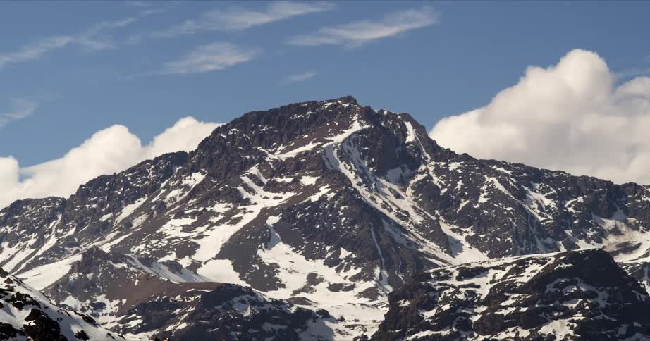 White clouds move behind the snowy mountain in timelapse