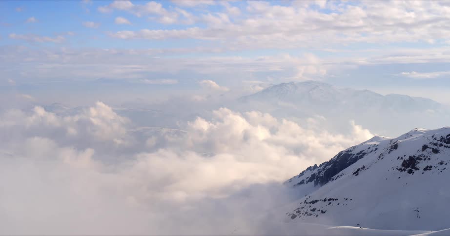 Clouds roll over winter sunset mountains in timelapse