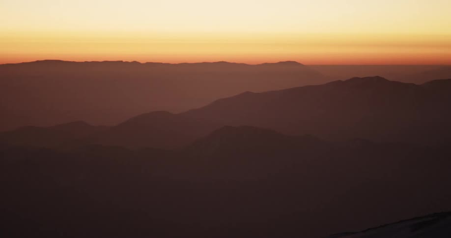 A mountain landscape at sunset with orange skies