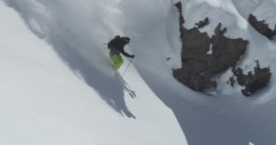 A person is downhill skiing through powder