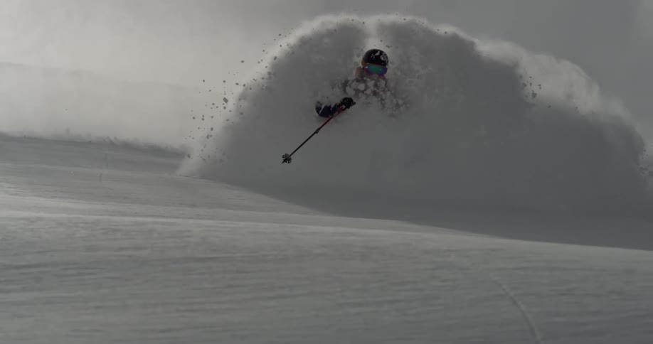 Snow flying behind a man as he skis down a hill