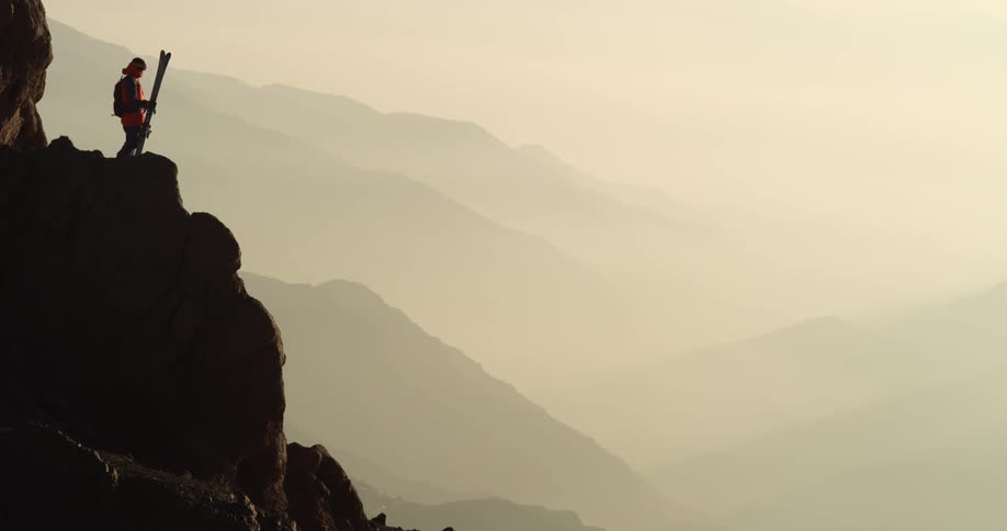 A skier stands above a mountain vista