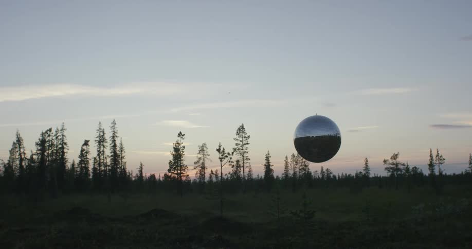 A small silver glove floats over a field at sunset