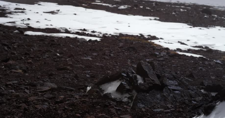 Wind and snow blow through a rocky landscape