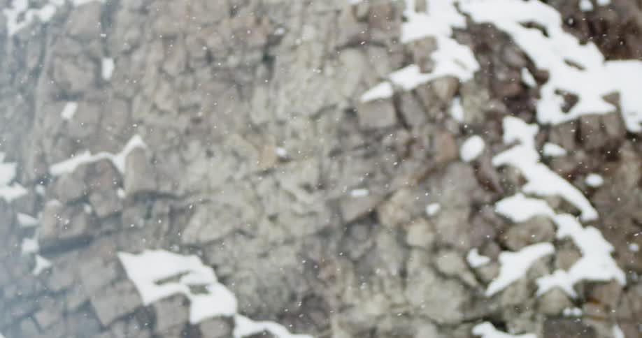 Snow falling in front of a rocky canyon wall in winter